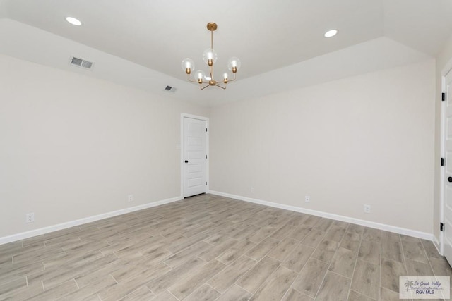 empty room with a notable chandelier and light wood-type flooring