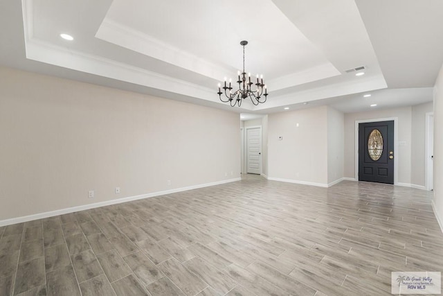 unfurnished living room featuring a chandelier and a tray ceiling