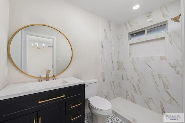 bathroom featuring vanity, toilet, and tiled shower