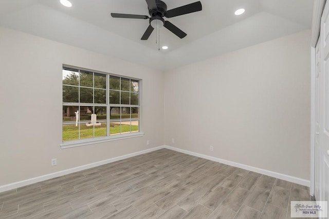 spare room with ceiling fan, light wood-type flooring, and a tray ceiling