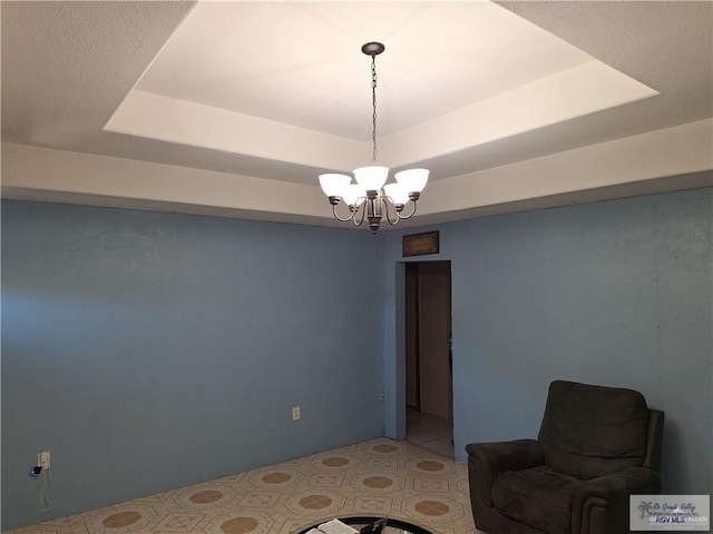 living area featuring a notable chandelier and a raised ceiling