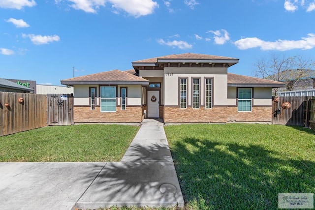 view of front of property featuring a gate, fence, a front lawn, and stucco siding