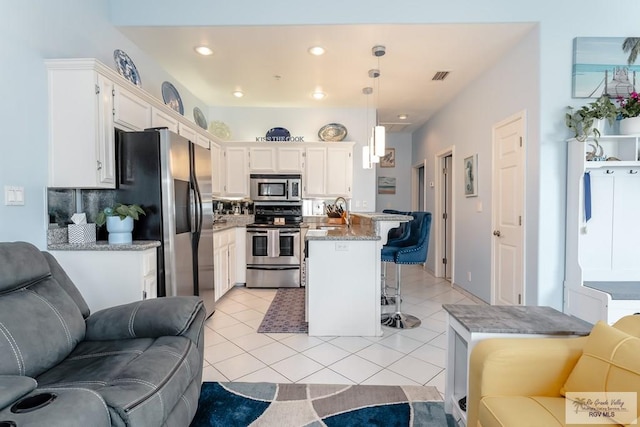 kitchen with a kitchen bar, appliances with stainless steel finishes, decorative backsplash, pendant lighting, and a kitchen island