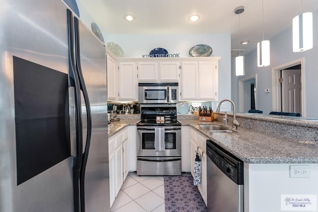 kitchen with stainless steel appliances, sink, light tile patterned floors, white cabinetry, and hanging light fixtures