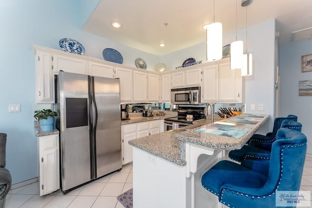 kitchen with kitchen peninsula, appliances with stainless steel finishes, light tile patterned floors, pendant lighting, and white cabinetry