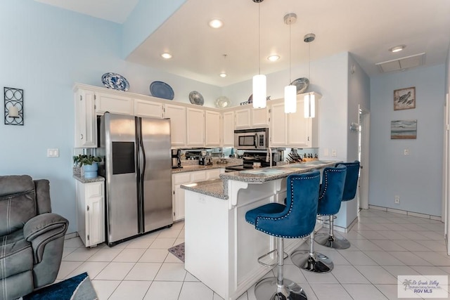 kitchen with stainless steel appliances, white cabinets, kitchen peninsula, decorative light fixtures, and light tile patterned floors