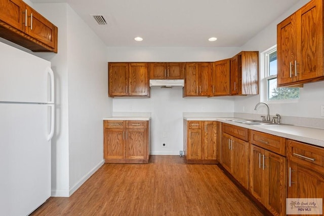 kitchen featuring sink, light hardwood / wood-style floors, and white fridge