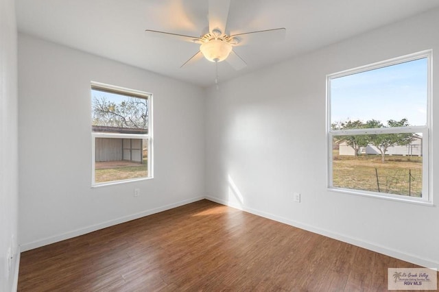 spare room with ceiling fan, dark hardwood / wood-style flooring, and a wealth of natural light