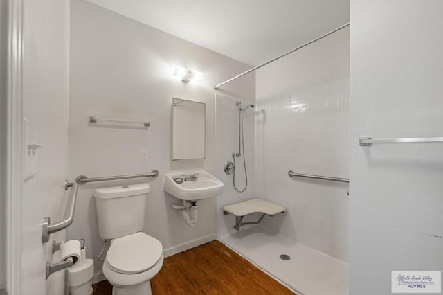 bathroom featuring wood-type flooring, tiled shower, and toilet