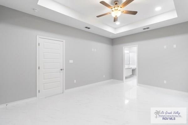 empty room featuring a raised ceiling and ceiling fan