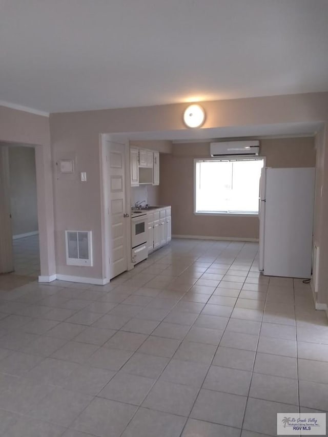5824 Southmost Rd, Brownsville, TX 78521 - kitchen with an AC wall unit, light tile patterned floors, white appliances, baseboards, and white cabinetry
