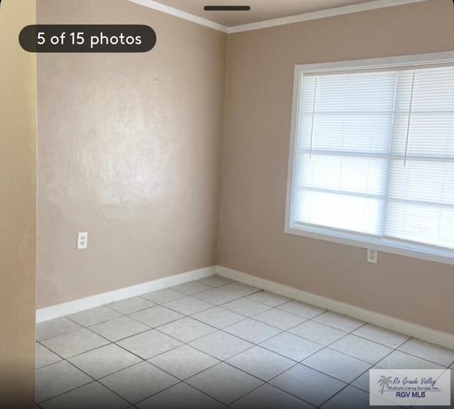 unfurnished room featuring light tile patterned floors and crown molding