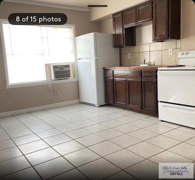 kitchen featuring dark brown cabinetry, tasteful backsplash, ornamental molding, cooling unit, and white appliances