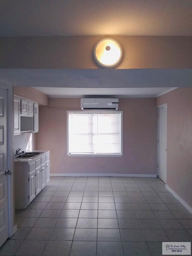 5824 Southmost Rd, Brownsville, TX 78521 - interior space featuring white cabinets, a sink, a wall unit AC, baseboards, and tile patterned flooring