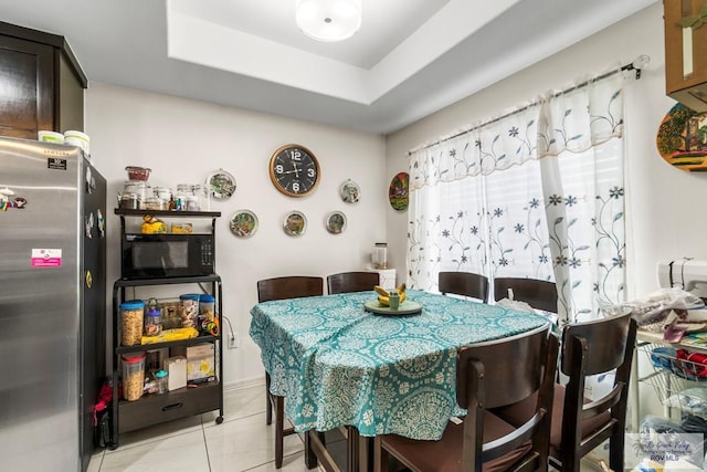 dining space featuring light tile patterned floors and a tray ceiling