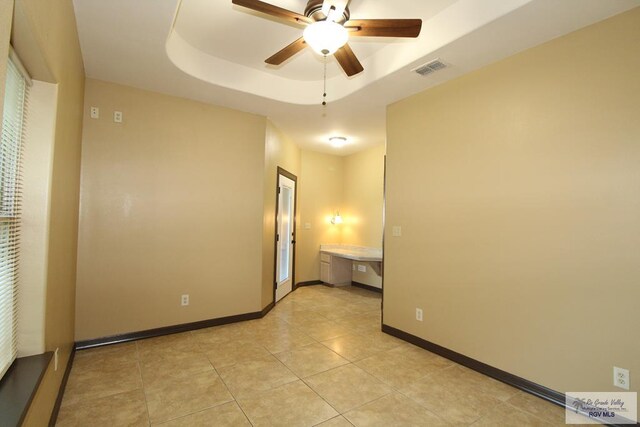 27281 Palm Blvd, Harlingen, TX 78552 - spare room featuring a ceiling fan, a tray ceiling, and light tile patterned floors