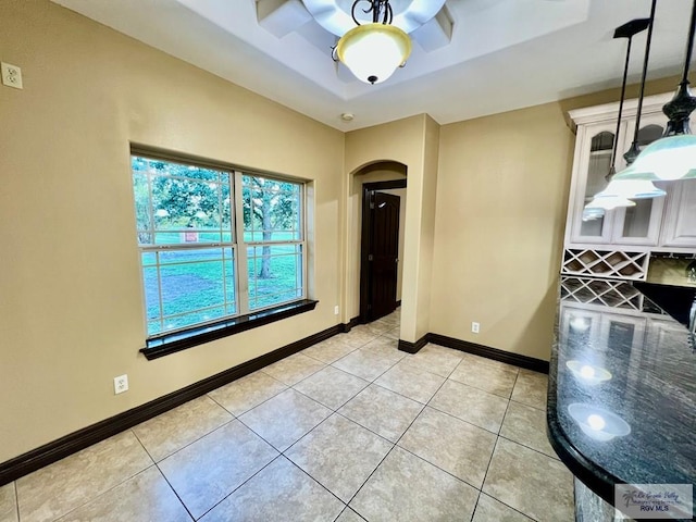 27281 Palm Blvd, Harlingen, TX 78552 - unfurnished dining area featuring arched walkways, a tray ceiling, and light tile patterned flooring