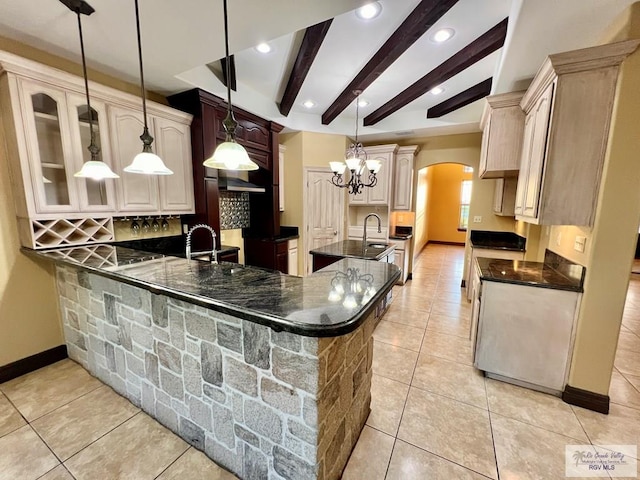 27281 Palm Blvd, Harlingen, TX 78552 - kitchen with arched walkways, decorative backsplash, light tile patterned flooring, beamed ceiling, and a center island with sink