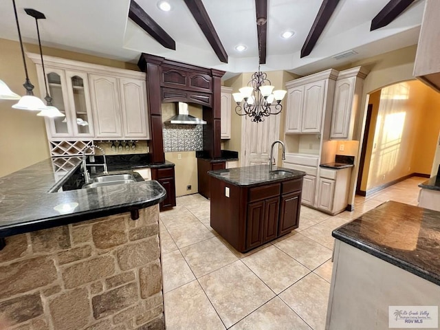 27281 Palm Blvd, Harlingen, TX 78552 - kitchen featuring arched walkways, tasteful backsplash, beamed ceiling, a kitchen island with sink, and a chandelier