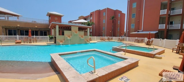 view of pool with a hot tub, a patio, and pool water feature