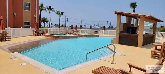 view of swimming pool with a hot tub and a patio area