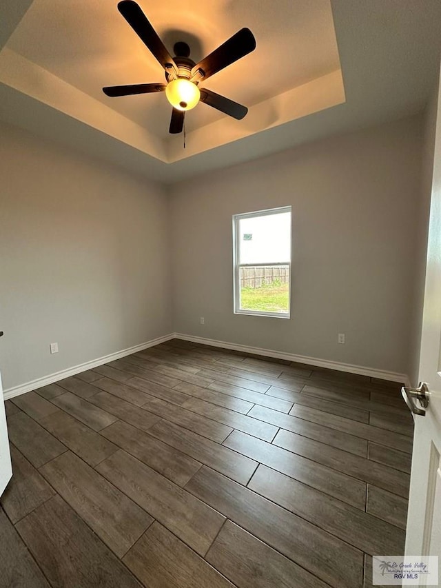 2299 Athens St, Brownsville, TX 78520 - spare room featuring a tray ceiling, a ceiling fan, and dark wood-style flooring