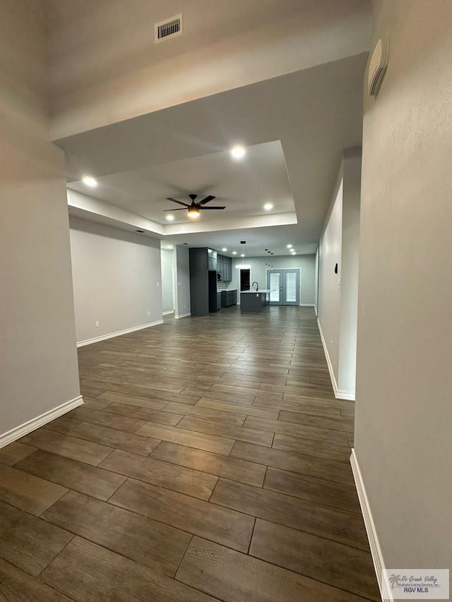 unfurnished living room with a tray ceiling and ceiling fan