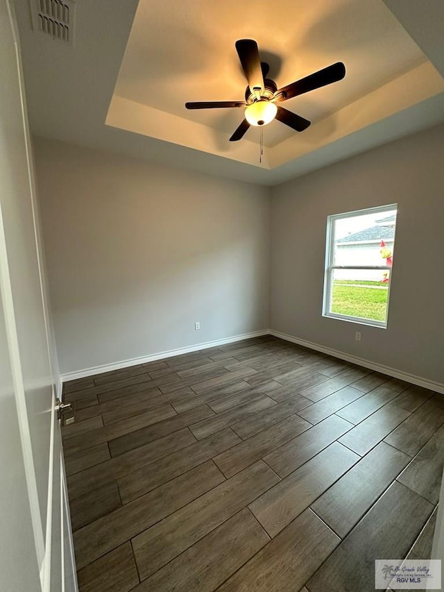 2299 Athens St, Brownsville, TX 78520 - empty room featuring a tray ceiling, a ceiling fan, and dark wood-type flooring