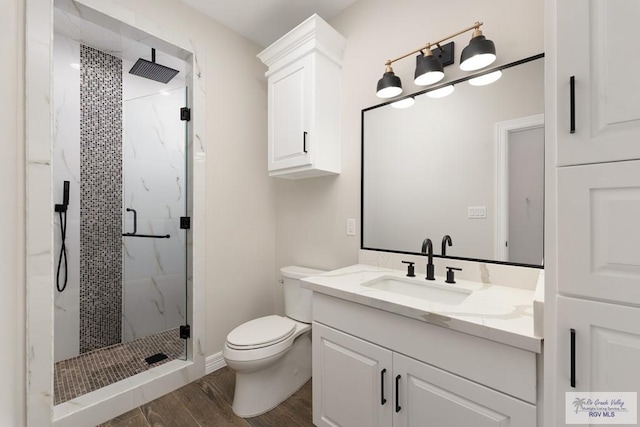 bathroom featuring toilet, vanity, a shower with shower door, and hardwood / wood-style flooring