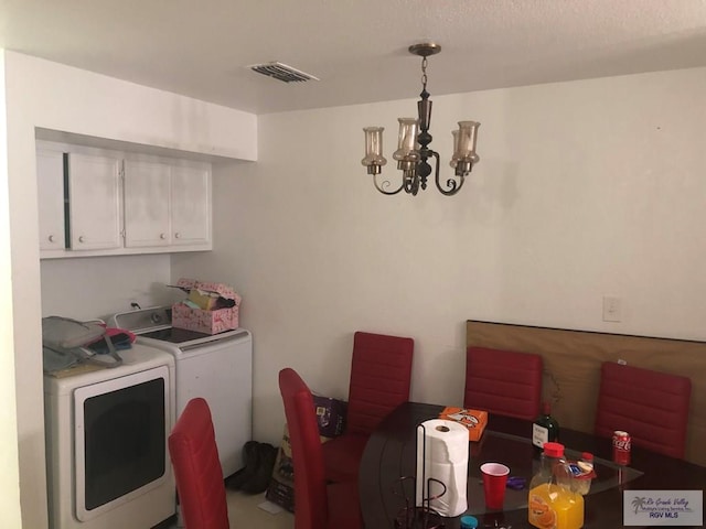 laundry area featuring washer and clothes dryer, cabinets, and a notable chandelier