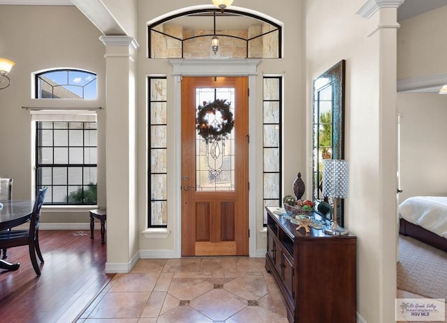 foyer featuring light hardwood / wood-style floors, ornate columns, and a high ceiling