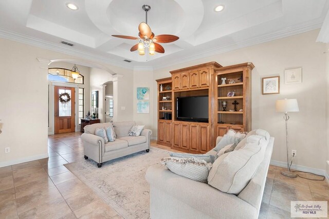 living room with coffered ceiling, a raised ceiling, ceiling fan, ornamental molding, and light tile patterned flooring