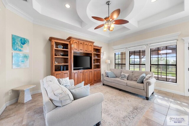 tiled living room featuring a raised ceiling, ceiling fan, and crown molding