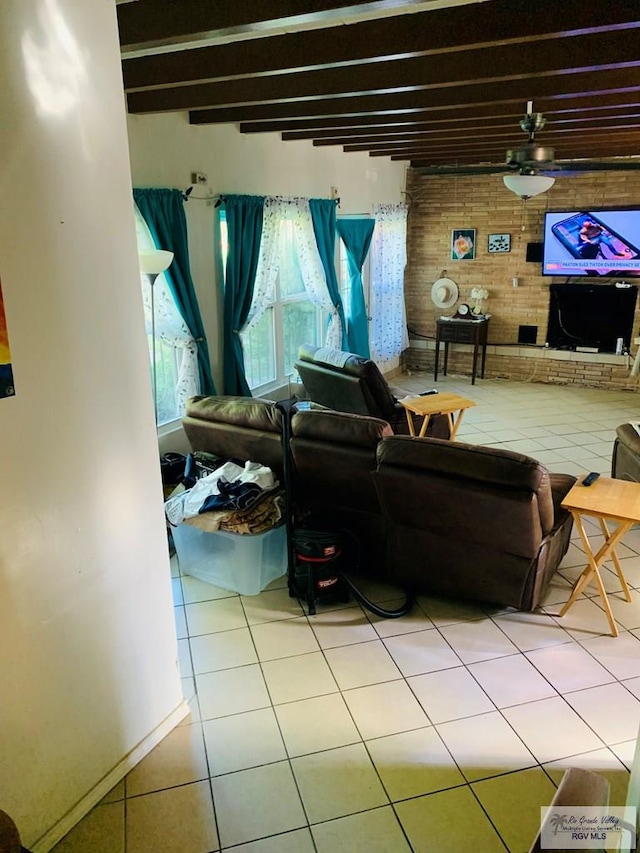 living room with beam ceiling, light tile patterned floors, ceiling fan, and brick wall