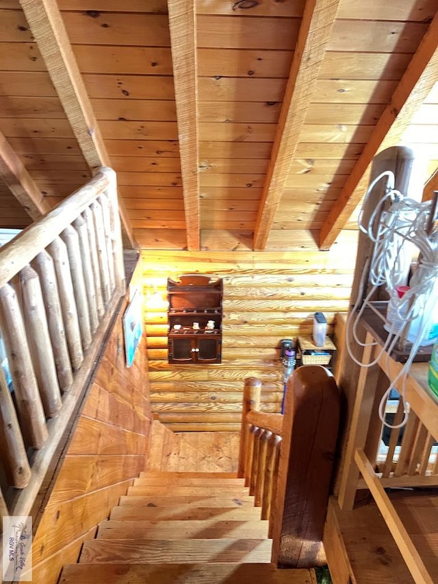 stairs with beamed ceiling, hardwood / wood-style floors, rustic walls, and wooden ceiling