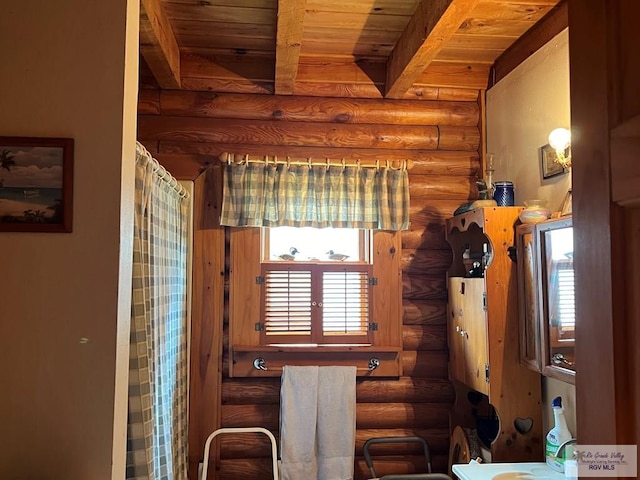 interior space with beamed ceiling, wooden ceiling, and rustic walls