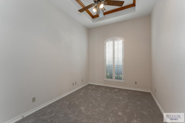 carpeted empty room with ceiling fan and a tray ceiling