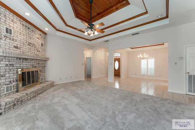 unfurnished living room with a raised ceiling, light colored carpet, and a brick fireplace