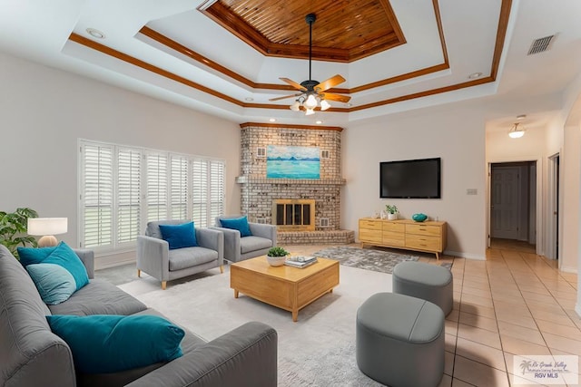 tiled living room featuring ceiling fan, a fireplace, and a tray ceiling