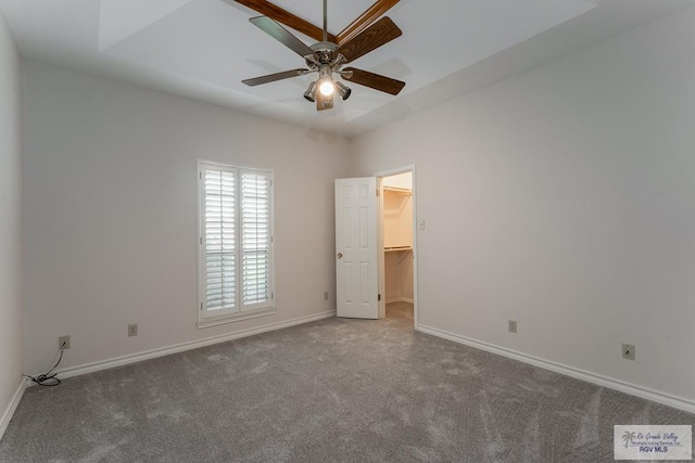 unfurnished bedroom featuring carpet floors, a closet, a spacious closet, and ceiling fan