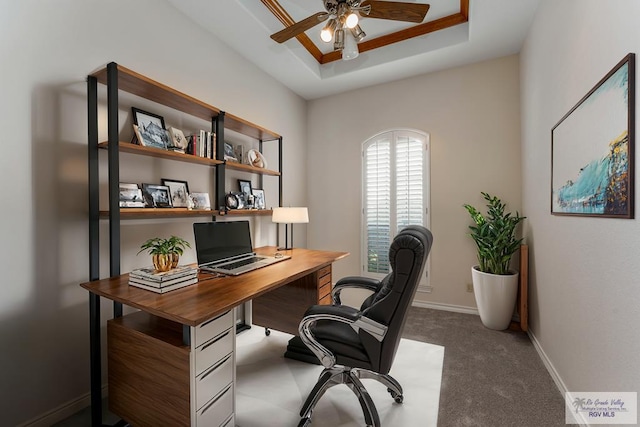 office area featuring a raised ceiling, ceiling fan, and carpet flooring