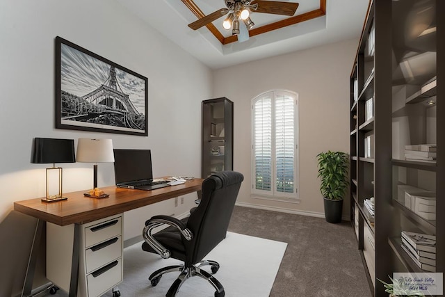 home office featuring ceiling fan, dark carpet, and a raised ceiling