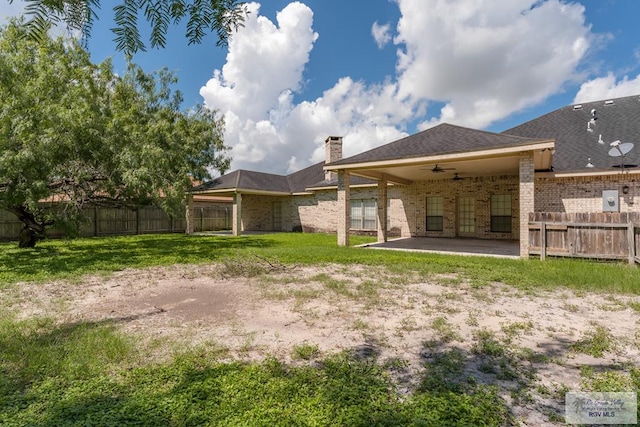 back of property with a yard, ceiling fan, and a patio area