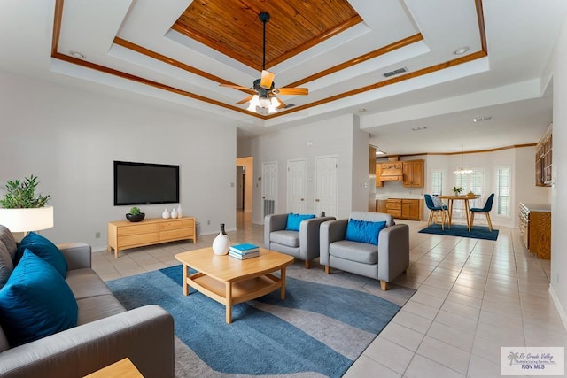 tiled living room featuring ceiling fan, a raised ceiling, and ornamental molding