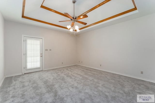 unfurnished room with a tray ceiling, ceiling fan, light carpet, and ornamental molding