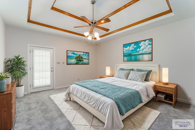 carpeted bedroom with a tray ceiling, ceiling fan, and ornamental molding