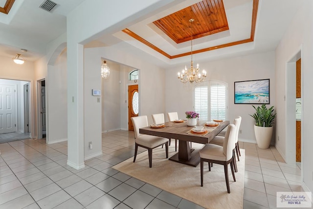 tiled dining space featuring a raised ceiling, wood ceiling, crown molding, and a chandelier