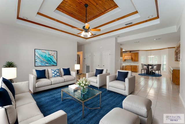 tiled living room with a tray ceiling, ceiling fan, and crown molding