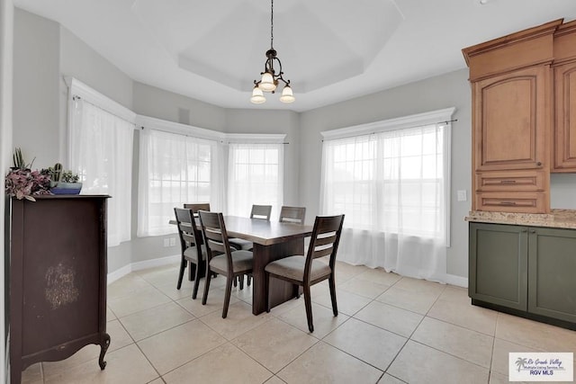 tiled dining area featuring a notable chandelier and a raised ceiling