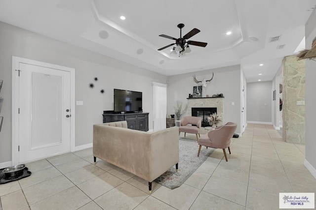 living room with light tile patterned floors, a tray ceiling, and a fireplace